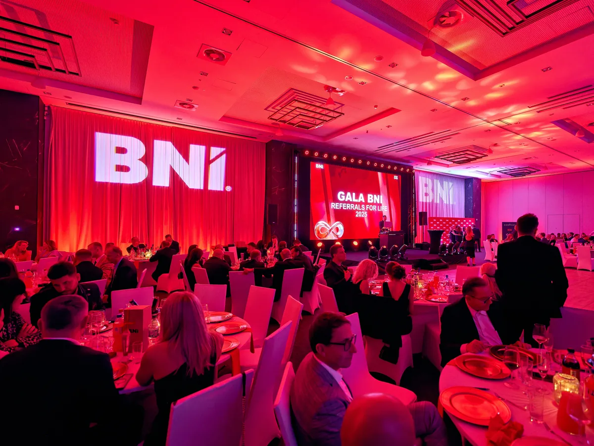 Ośmioro Członków BNI w strojach wieczorowych pozuje przy ściance z logotypami BNI.