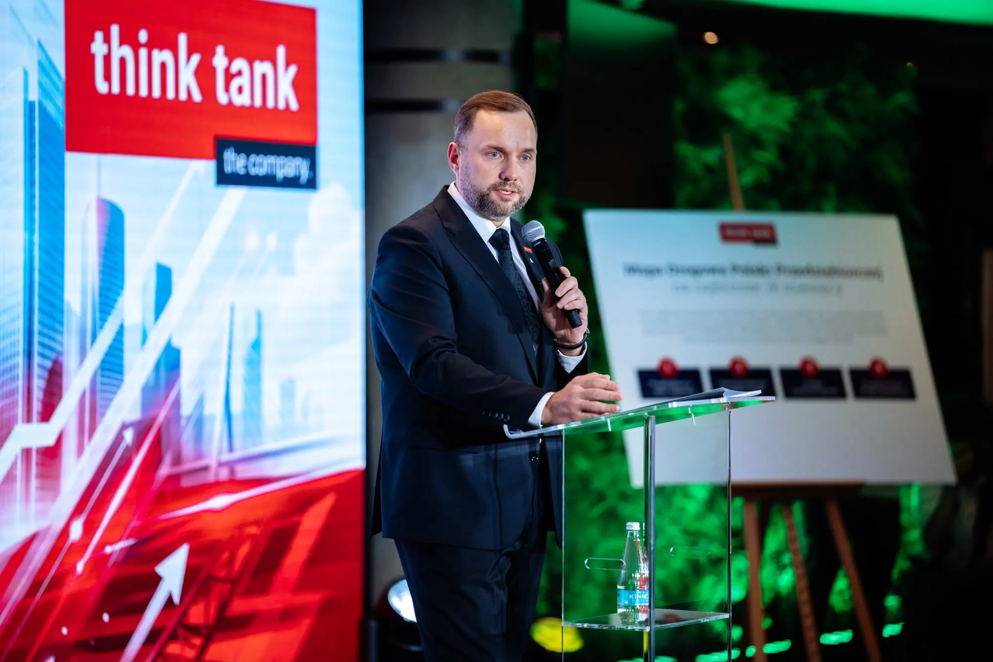 Mówca przy szklanej mównicy z logo Think Tank.